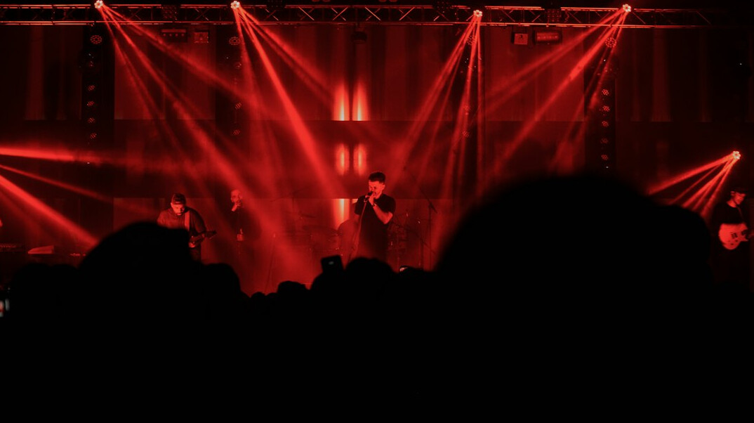 Concert stage with bright lights and silhouettes of an audience
